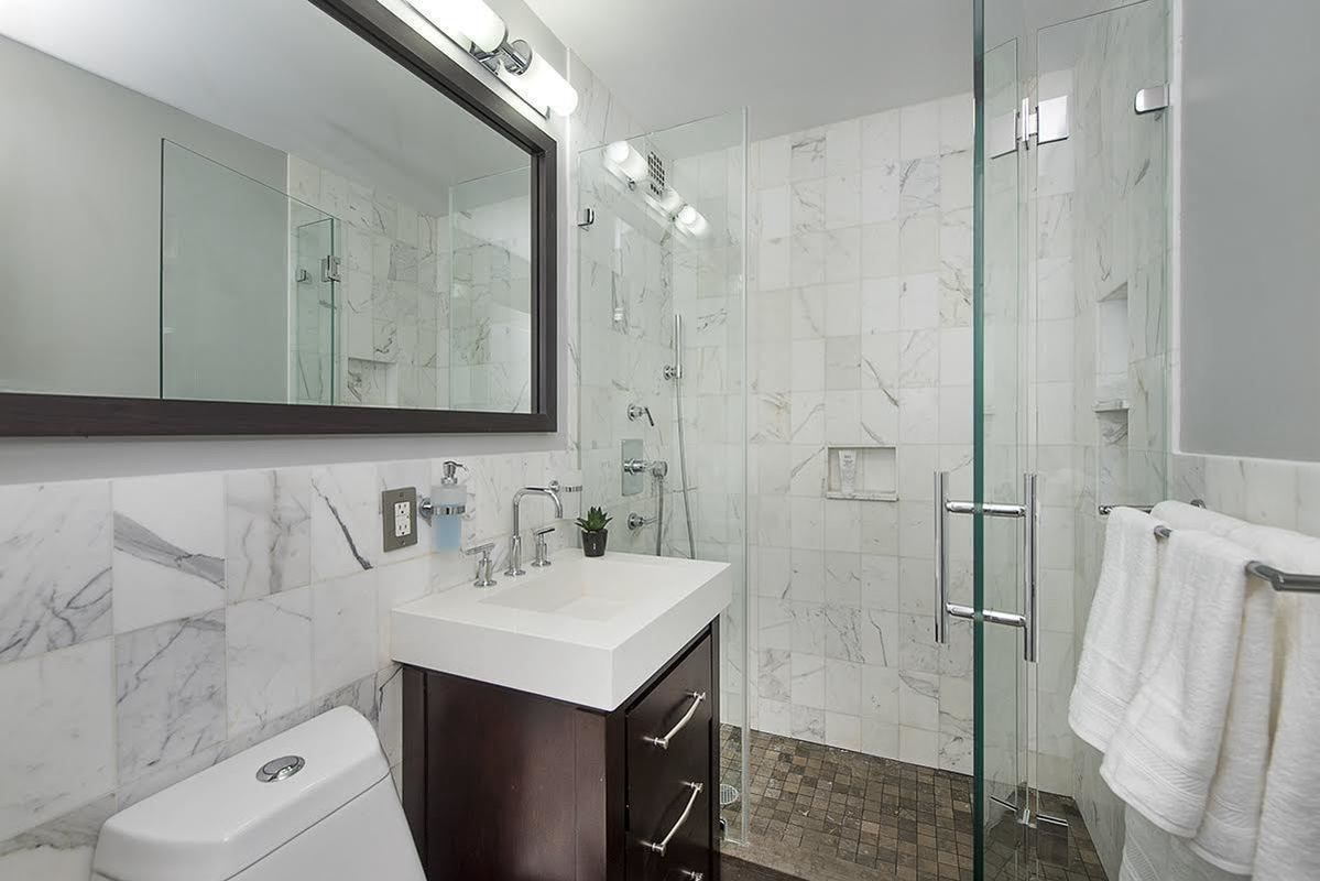 Marble bathroom with glass shower by The Slate Contracting Corp.